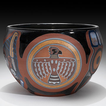 a ceramic bowl with an eagle depicted on it - glazed in blacks, browns, golds, blues and grays
